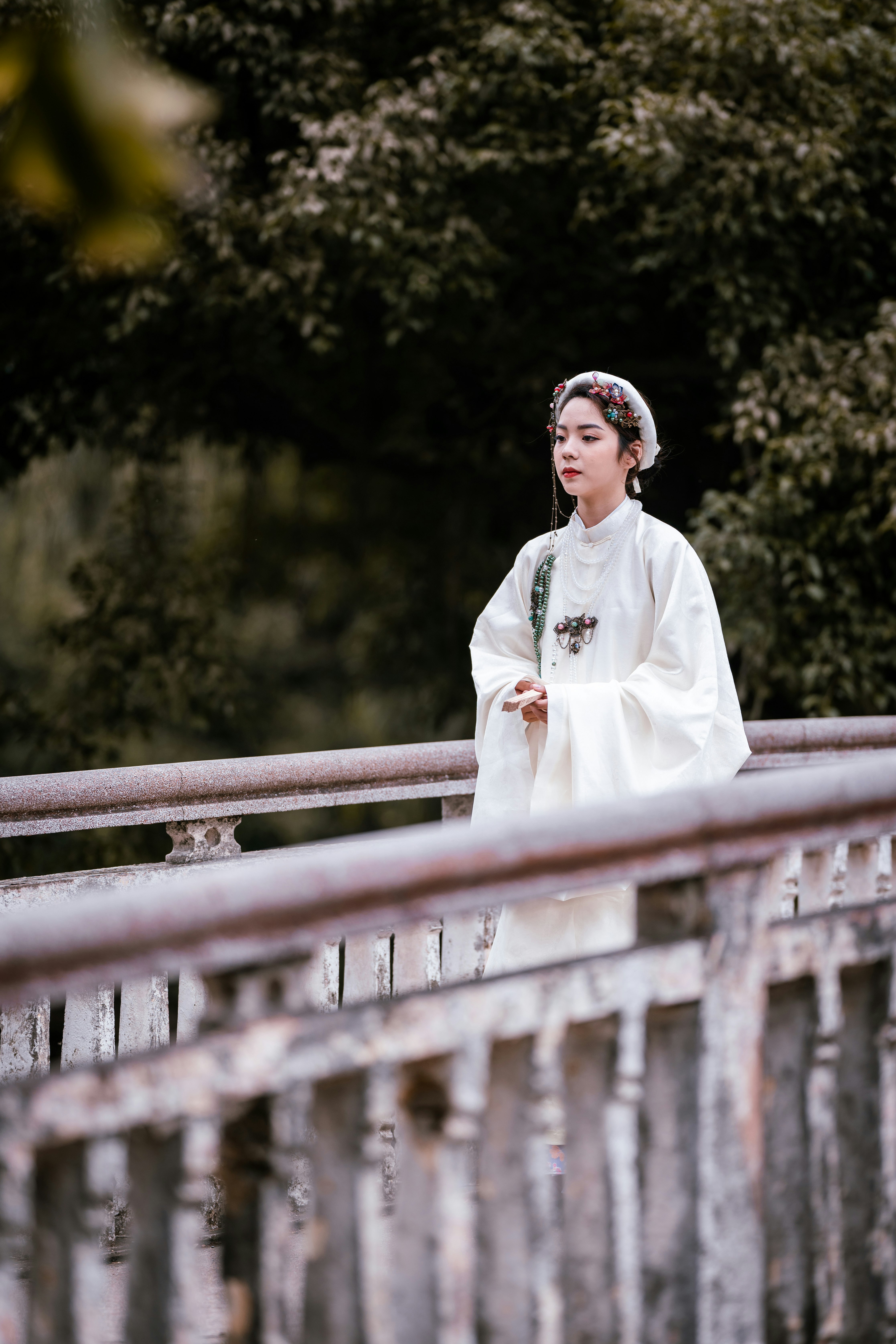 woman in white long sleeve dress standing on brown wooden bridge during daytime